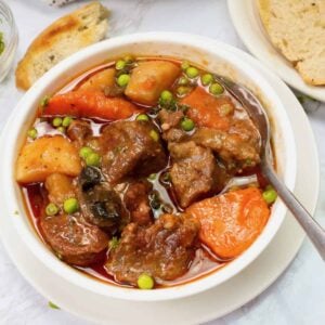 Insanely delicious slow cooker lamb stew in a white bowl with homemade bread