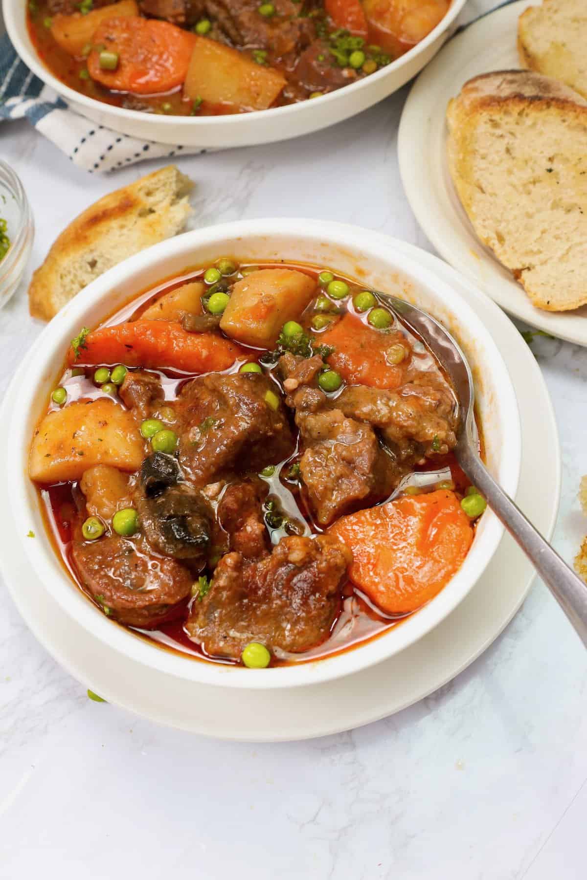 Insanely delicious slow cooker lamb stew in a white bowl with homemade bread