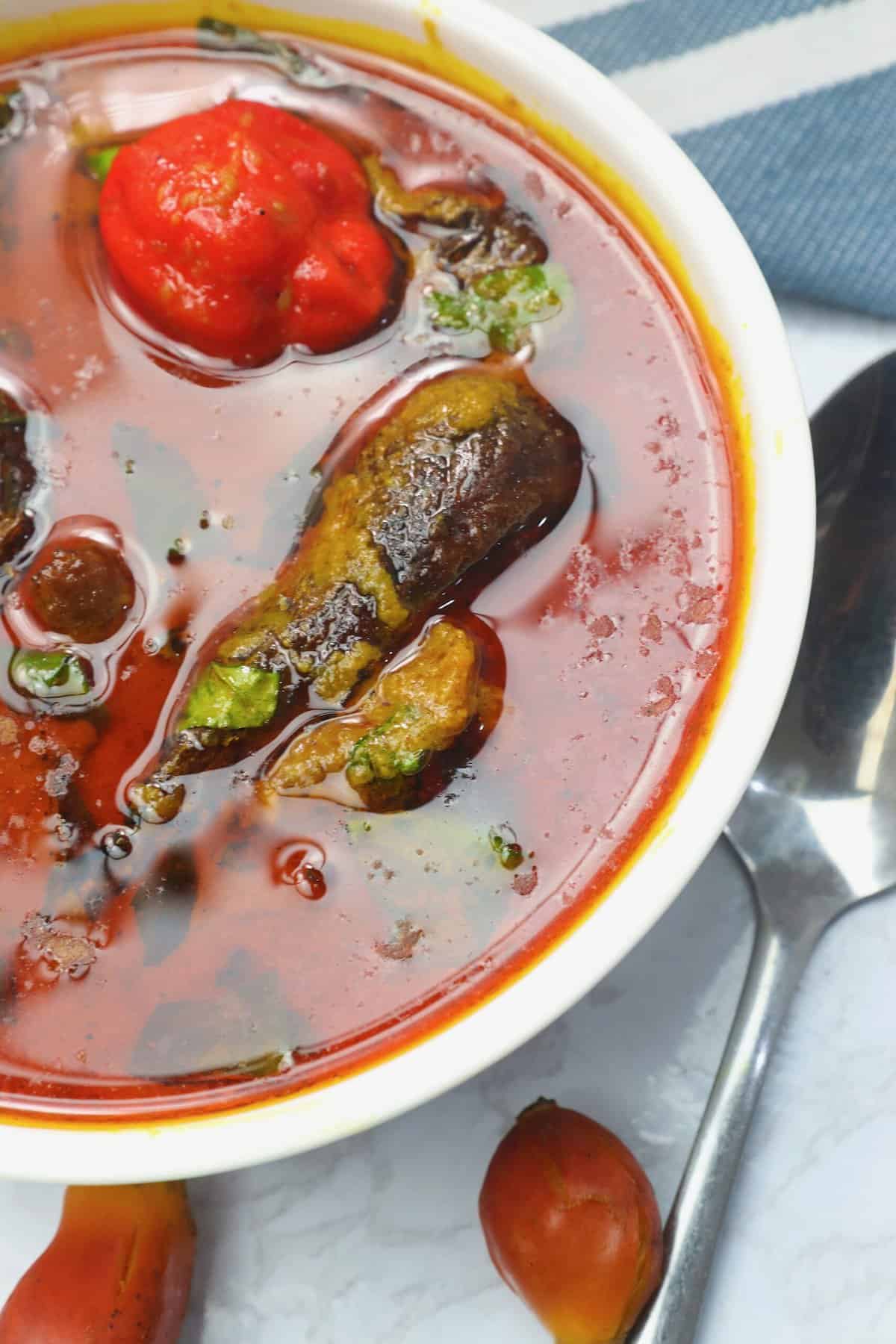 A mouthwatering bowl of palm nut soup (banga) with an optional scotch bonnet pepper