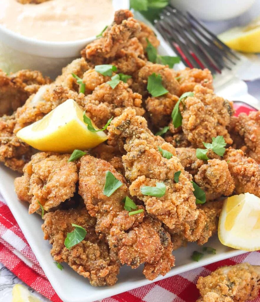 Enjoying a stack of delectable fried oysters with lemon wedges and sauce