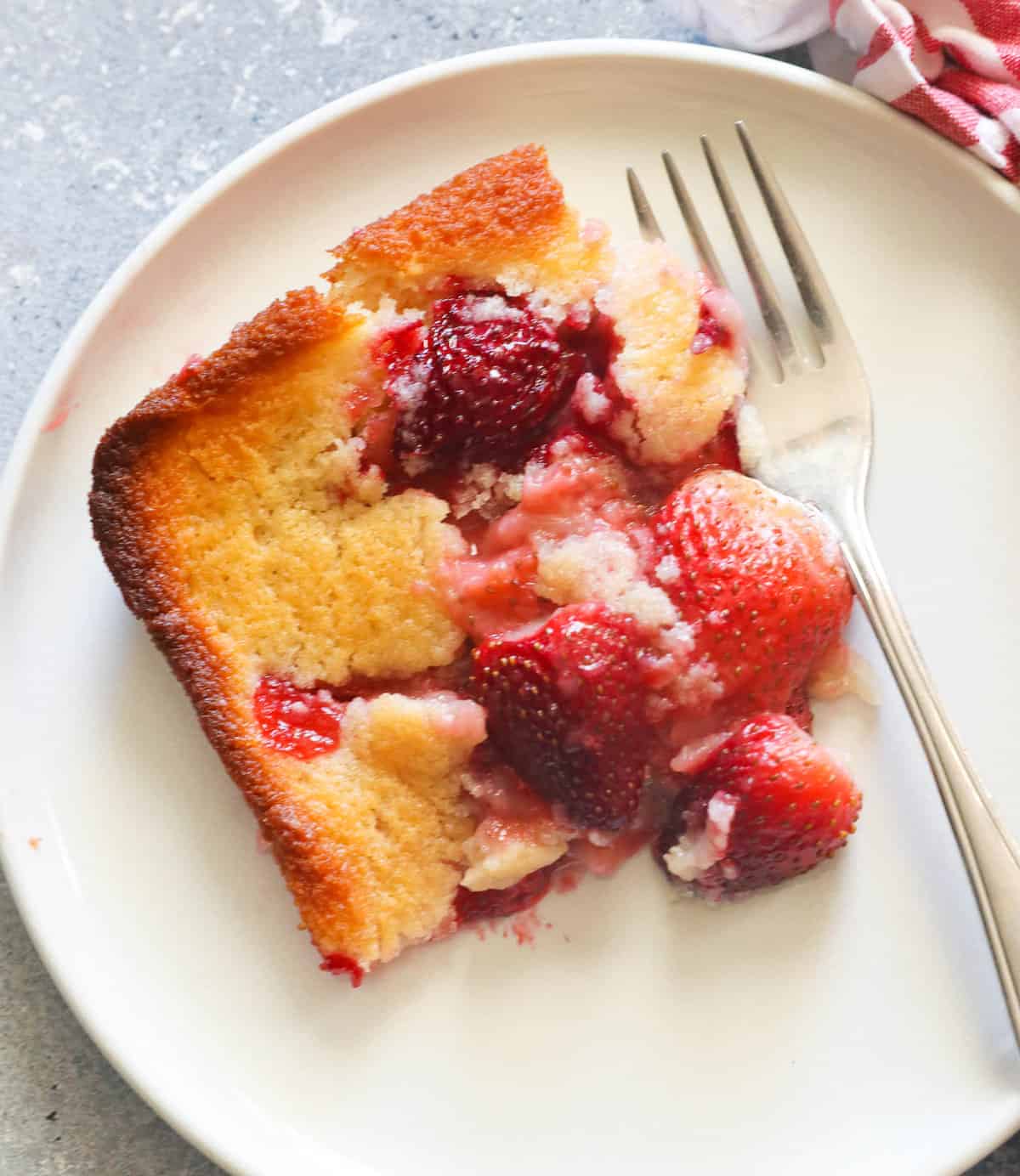 A decadent slice of strawberry cobbler freshly served on a white plate