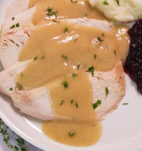 Drizzling easy turkey gravy without drippings over freshly roasted turkey breast with mashed potatoes