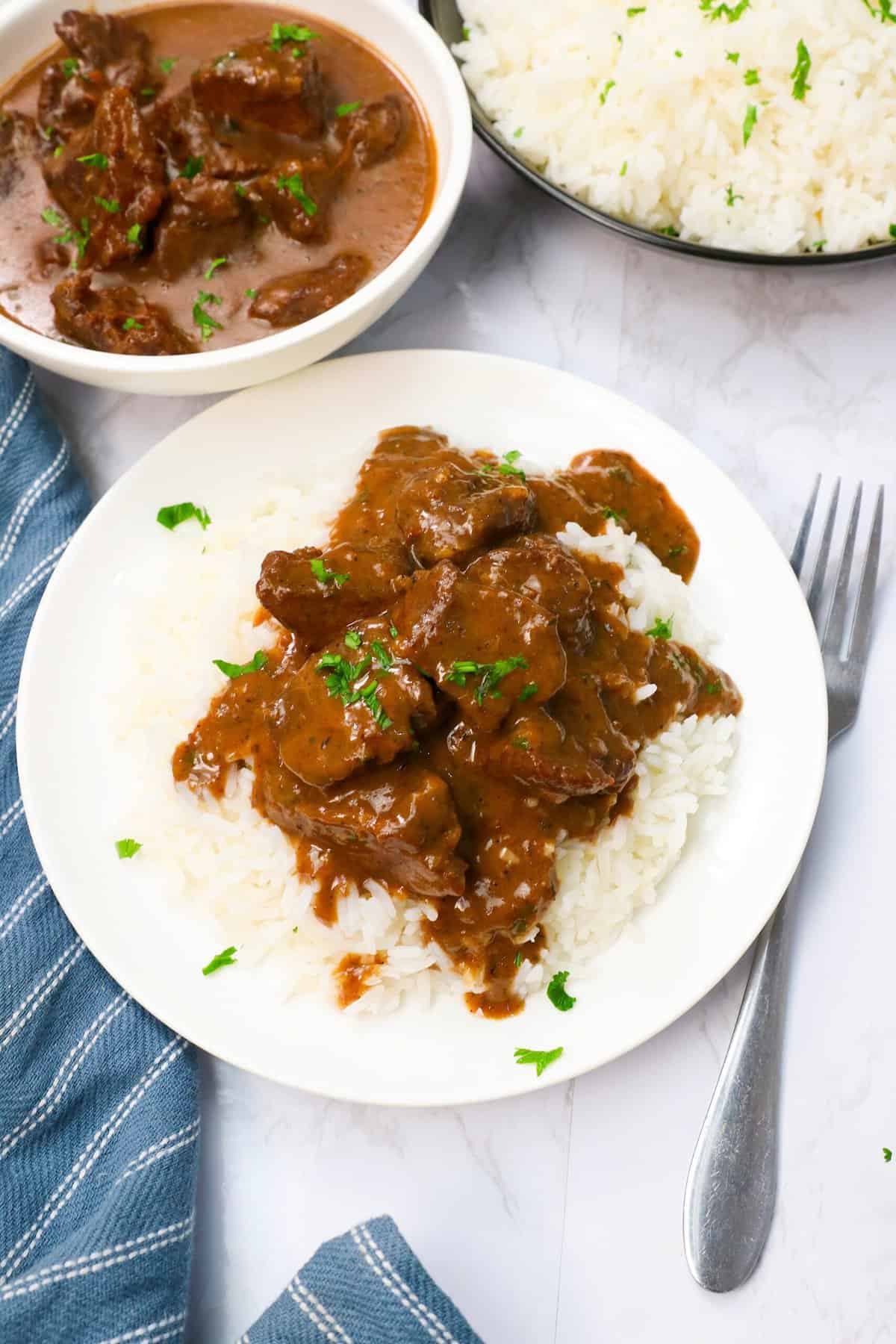 Dishing up beef tips on a bed of steaming hot rice