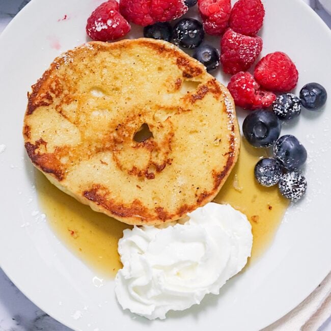 Enjoying a satisfying French Toast Bagels with whipped cream and berries