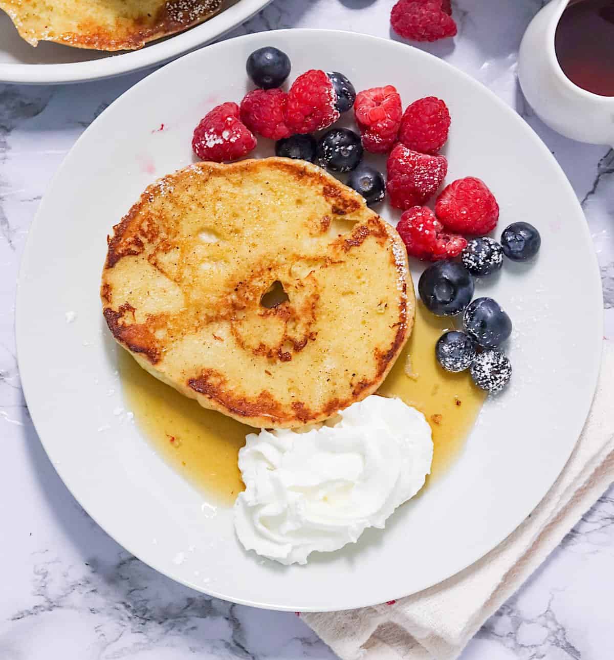 Enjoying a satisfying French Toast Bagels with whipped cream and berries