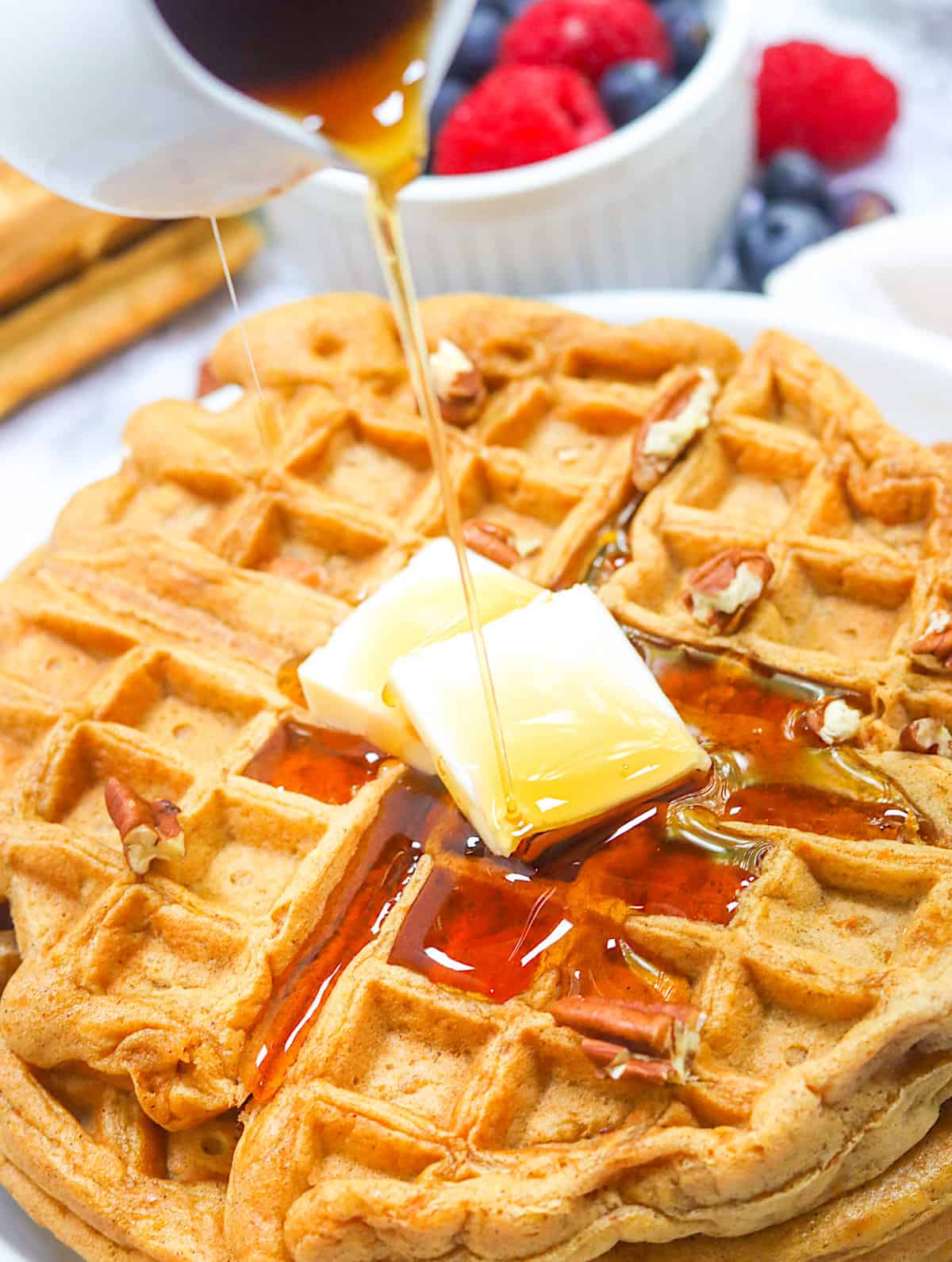 Drizzling decadent maple syrup over sweet potato waffles with butter