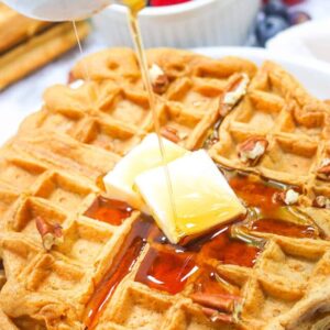 Drizzling decadent maple syrup over sweet potato waffles with butter