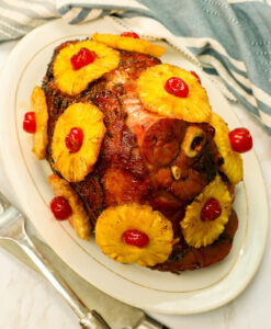 Succulent honey baked ham with caramelized pineapple slices and maraschino cherries