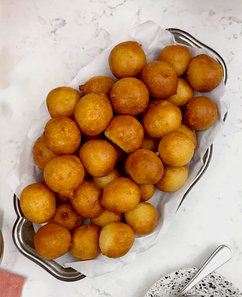 A platter loaded with freshly fried dough, puff puff.