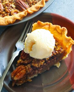 A slice of No Syrup Pecan Pie with ice cream on top for a decadent dessert