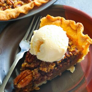 A slice of No Syrup Pecan Pie with ice cream on top for a decadent dessert