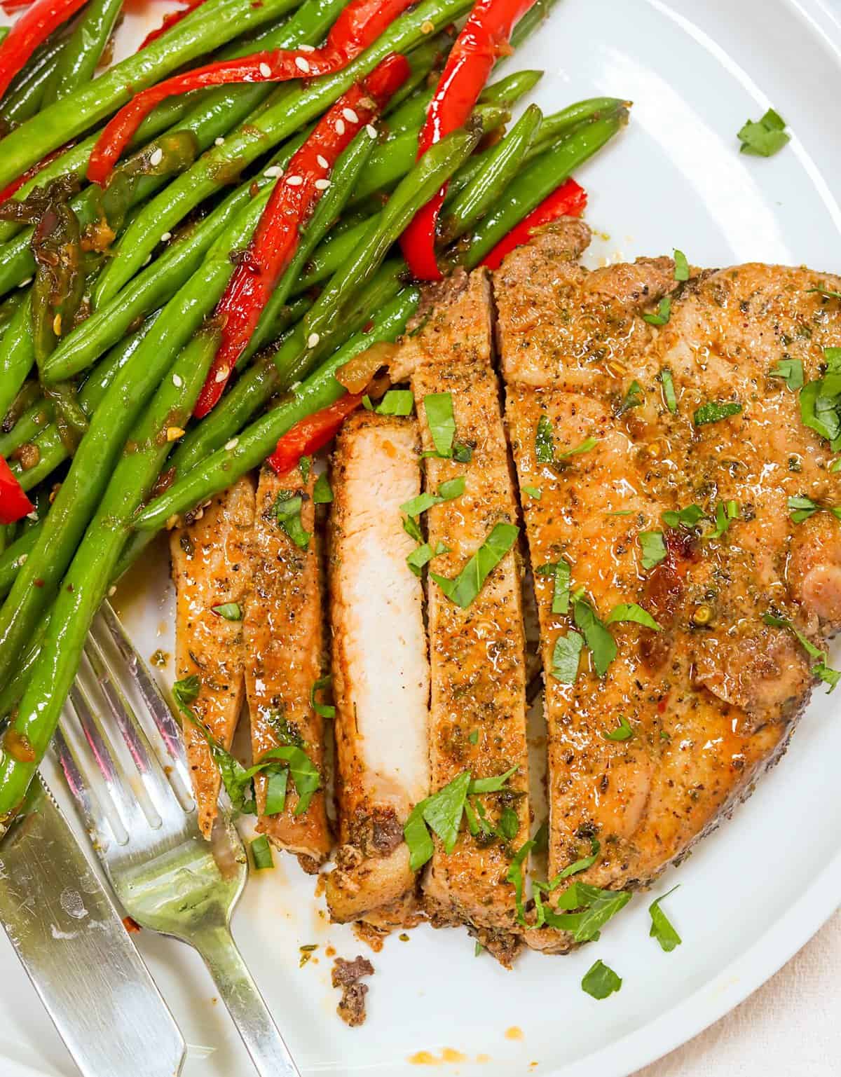 Enjoying straightforward 4-Ingredient Oven-Baked Pork Chops with roasted green beans and red peppers