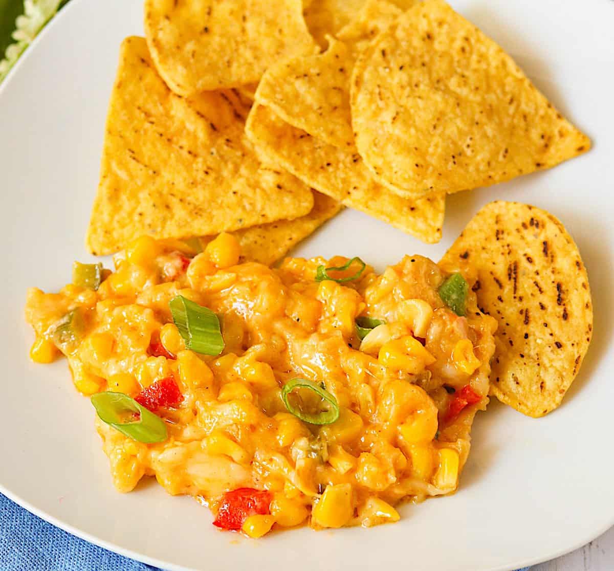 Insanely delicious hot corn dip on a white plate with homemade tortilla chips