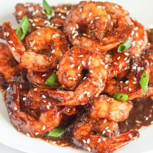 Enjoying steaming hot Teriyaki Shrimp garnished with sesame seeds and green onions on a white plate