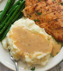 Enjoying chicken and mashed potatoes smothered in gravy wit roasted green beans on the side