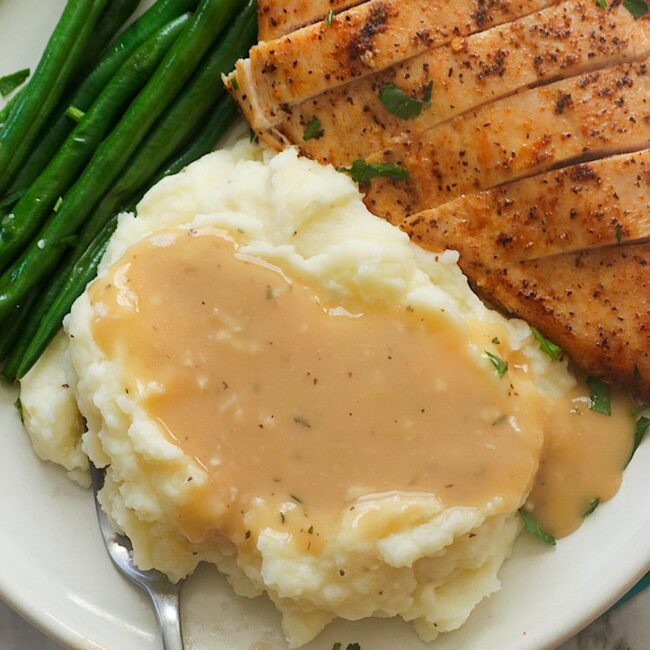 Enjoying chicken and mashed potatoes smothered in gravy wit roasted green beans on the side