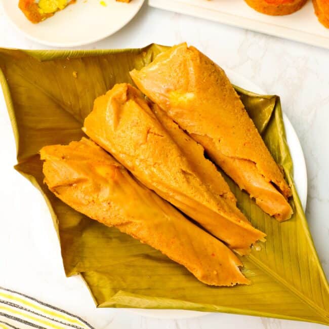 Unwrapping Moi Moi steamed in banana leaves with black-eyed pea pudding in ramekins in the background