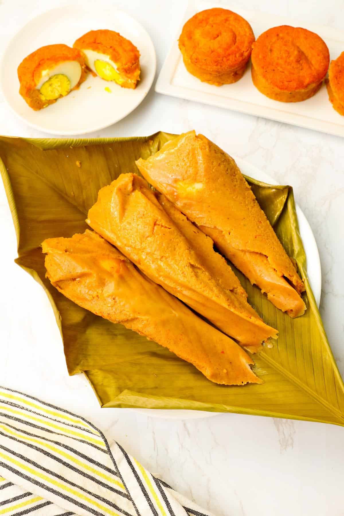 Unwrapping Moi Moi steamed in banana leaves with black-eyed pea pudding in ramekins in the background