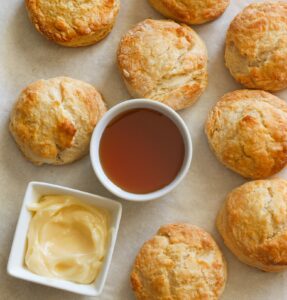 Insanely comforting Honey Butter Biscuits with honey butter and honey ready for drizzling