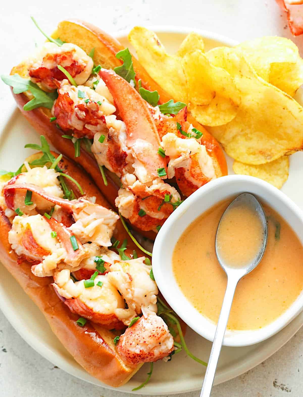 Serving up freshly assembled Connecticut Lobster Rolls with potato chips and extra butter sauce for a satisfying meal