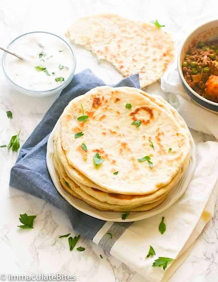 A stack of fresh flatbread with stew and a yogurt sauce