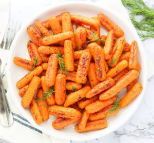 Naturally sweet Roasted Baby Carrots served up on a white plate ready to enjoy