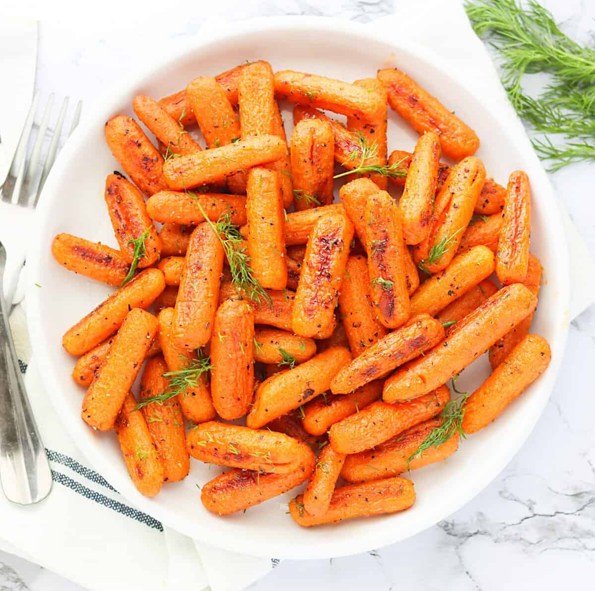 Naturally sweet Roasted Baby Carrots served up on a white plate ready to enjoy