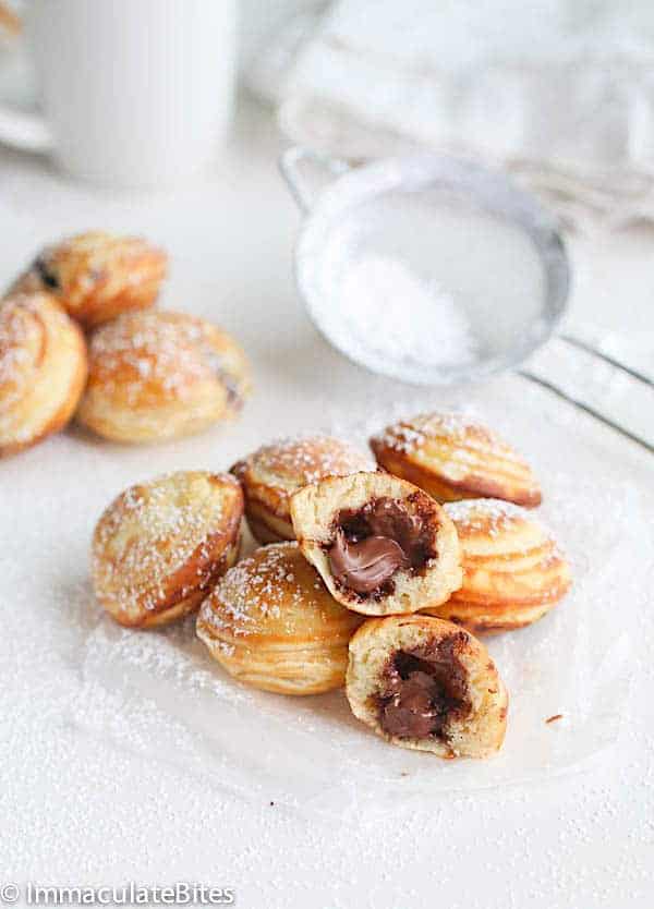 Breaking open Aebleskiver Danish Pancakes dusted with powdered sugar for an insanely delicious breakfast treat