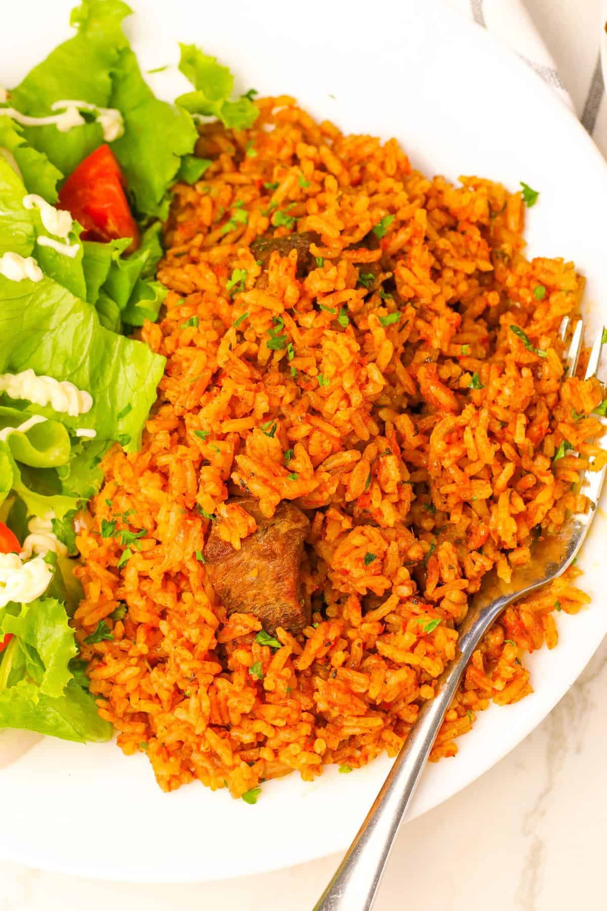 A delicious serving of Ghana jollof rice with a green salad for healthy soul food