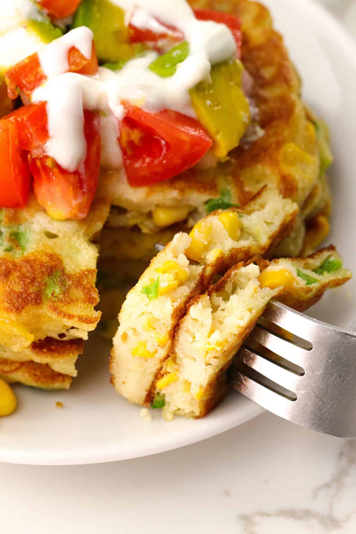 Take a bite of corn cake topped with sour cream, tomato, corn, and avocado