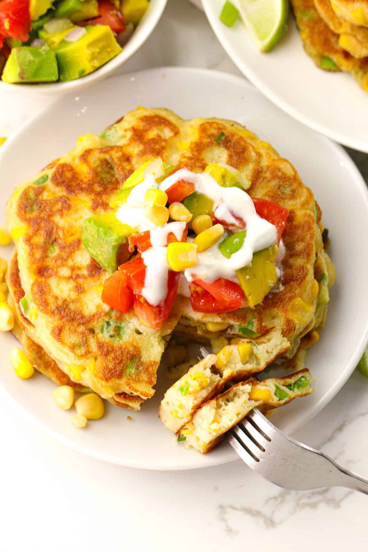 Enjoy a serving of corn cake topped with tomatoes, sour cream, avocado, and fresh corn.