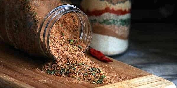 Spicy and flavorful Jamaican jerk seasoning spilling out of a glass jar and ready to spice up your meal