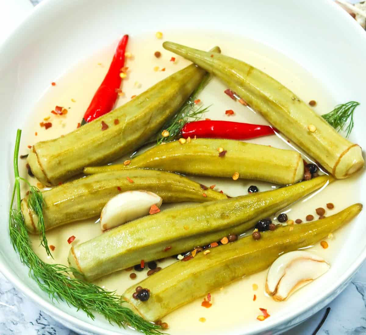 A bowl of pickled okra with chili peppers as a tasty snack or condiment