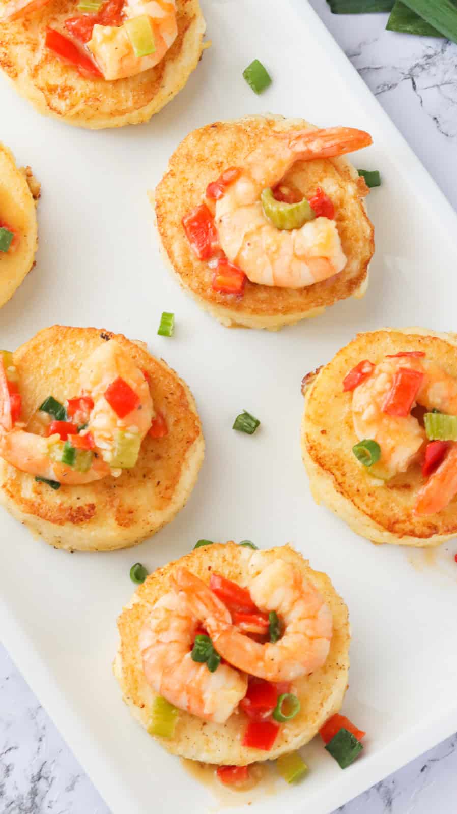A white platter filled with fast and easy grit cakes topped with shrimp