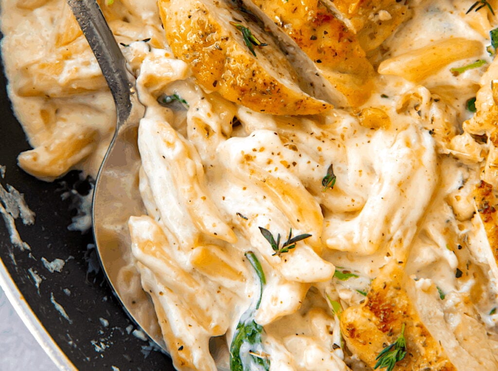Serving up creamy Alfredo sauce smothering penne pasta and topped with pan-fried chicken breast