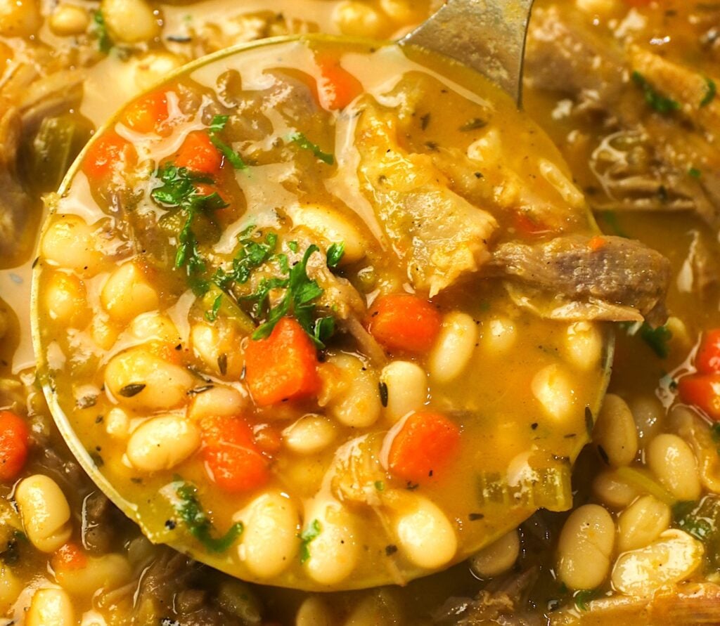 A healthy ladle full of navy bean soup with ham