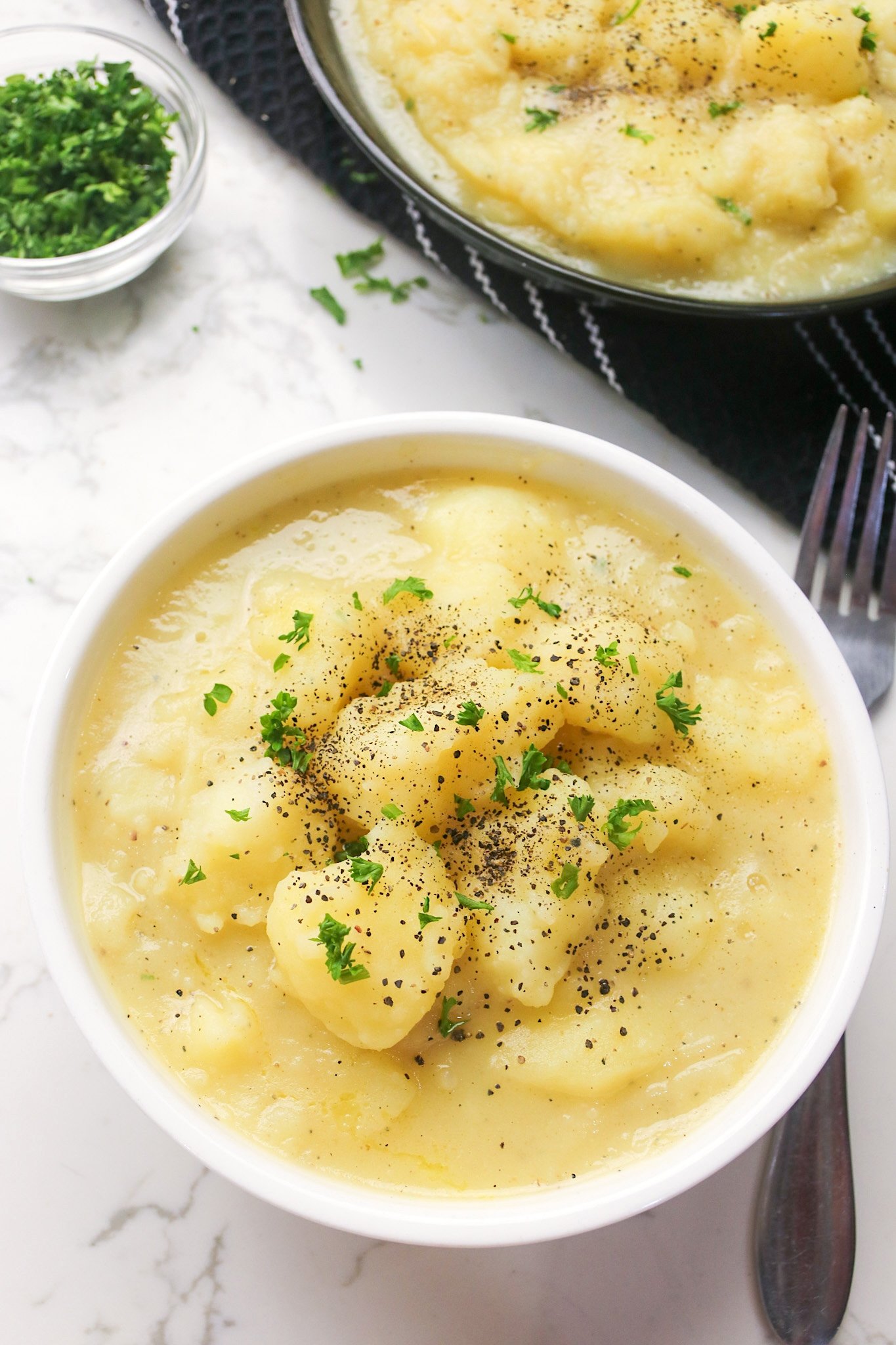 Serving up a delicious bowl of stewed potatoes sprinkled with black pepper and chopped parsley
