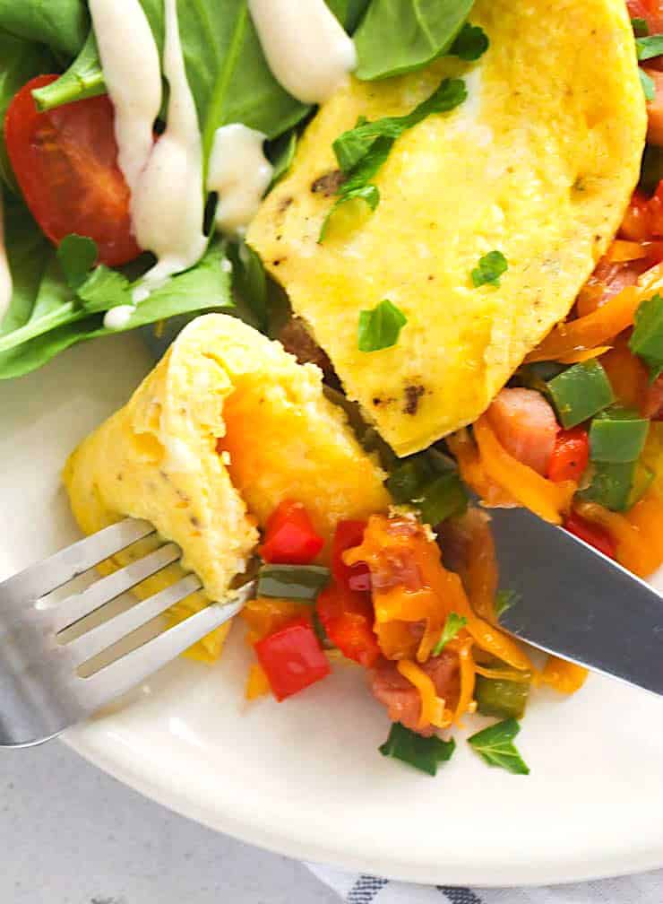 Forking into an omelet with a salad for a healthy hig-protein lunch.