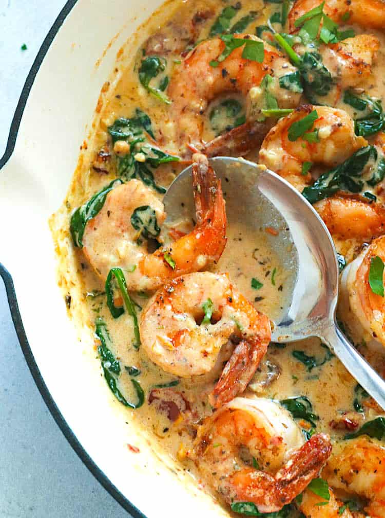 Creamy Tuscan shrimp in a decadent garlic sauce ready to serve over pasta.