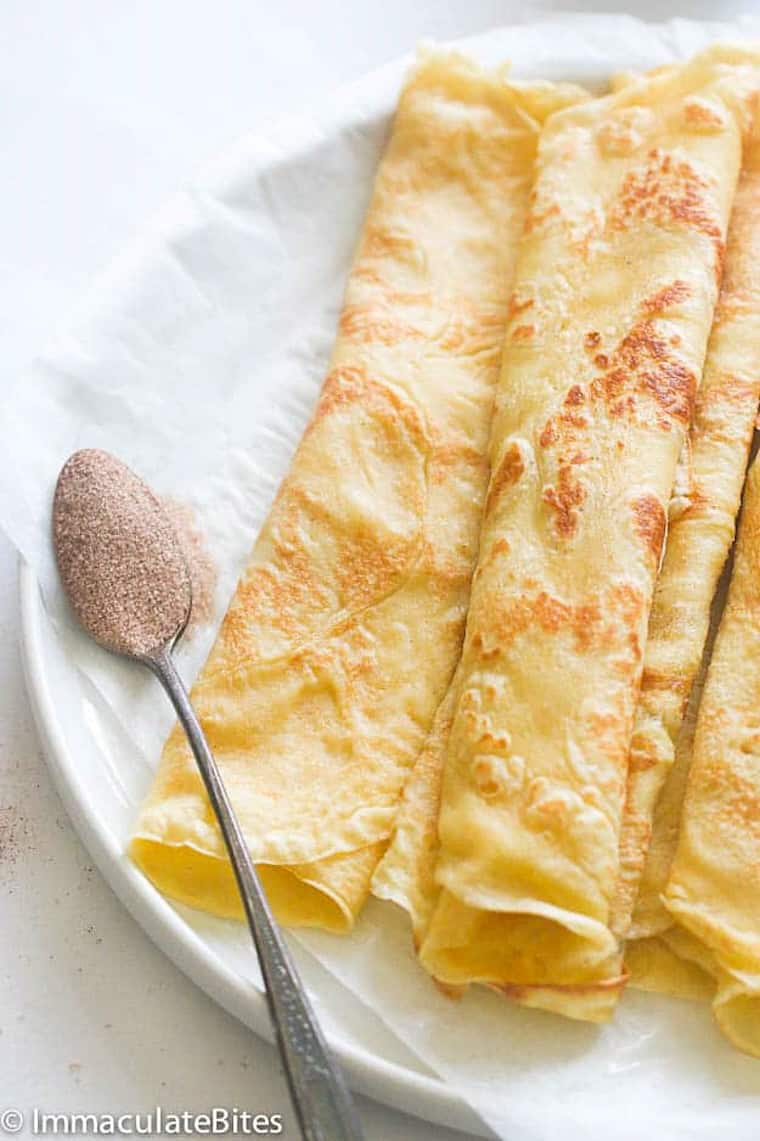 Rolling crepe-like pancakes with butter and cinnamon sugar.