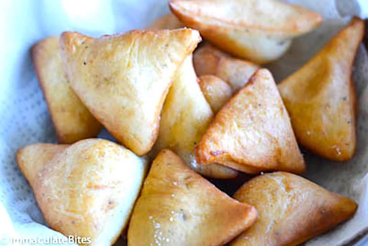 Freshly fried mandazi draining on a paper towel.