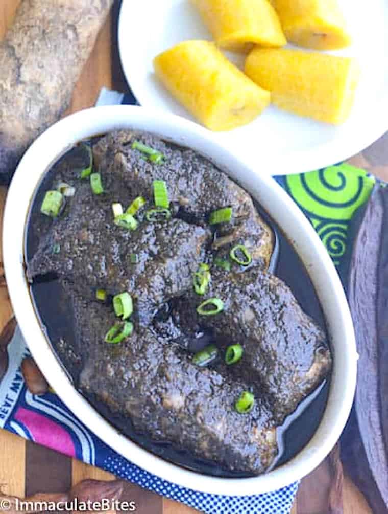 Mbongo Tchobi, a unique African spicy black stew ready to be served with boiled plantains.