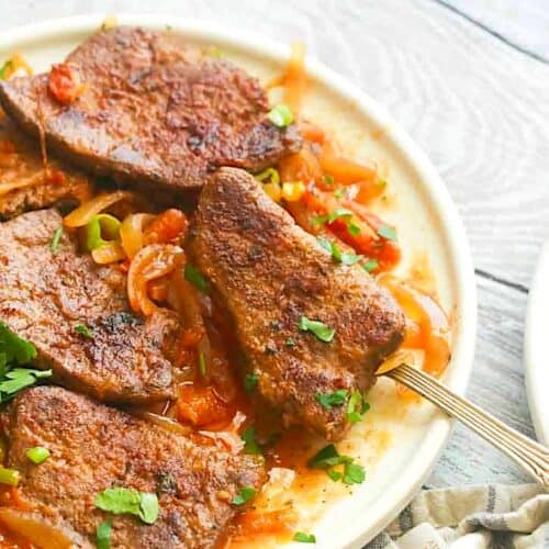 Diving into a platter filled with freshly made beef liver and onions with tomatoes.