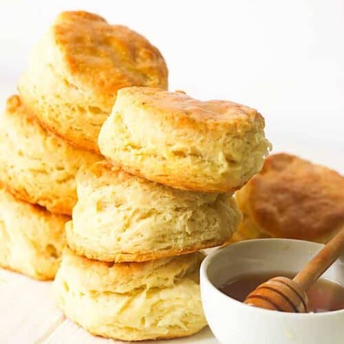 Enjoying a stack of light, flaky, freshly baked biscuits with honey.
