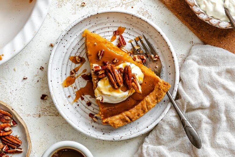 Serving up a silky smooth slice of condensed milk sweet potato pie topped with whipped cream, pecans, and caramel sauce.