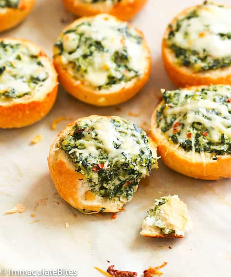 Biting into a bread stuffed with dip made from cheese and spinach.