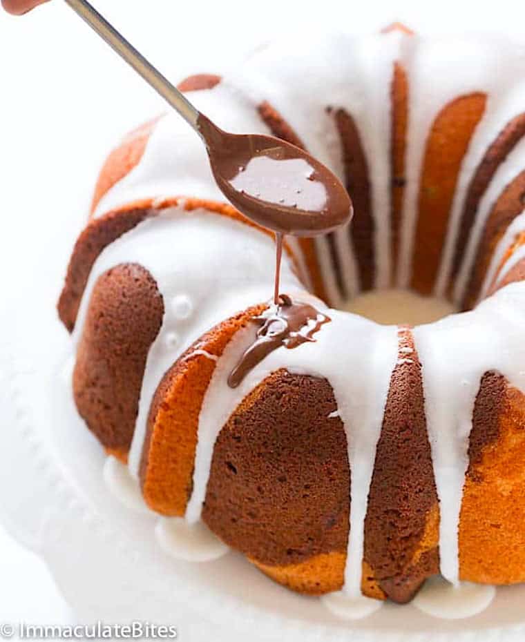 Drizzling a chocolate rum marble cake with vanilla and chocolate glaze.
