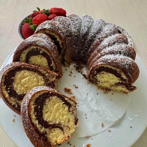 Slicing up a freshly baked marble cake and serving it with strawberries.