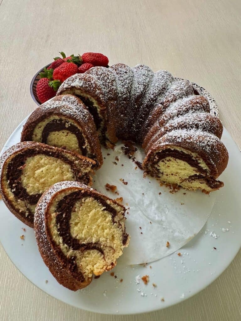 Slicing up a freshly baked marble cake and serving it with strawberries.