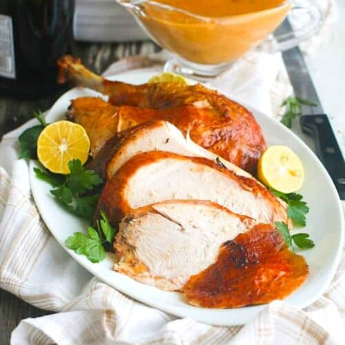 Beautifully roasted turkey on a white platter with gravy.